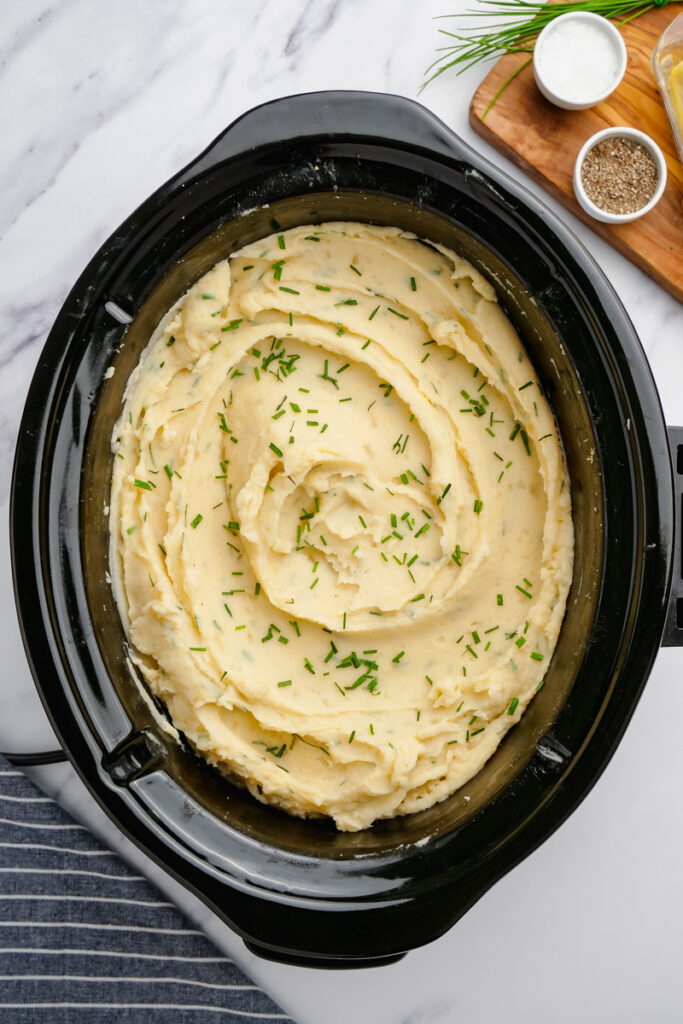 Slow Cooker Mashed Potatoes, ready to serve in a black slow cooker