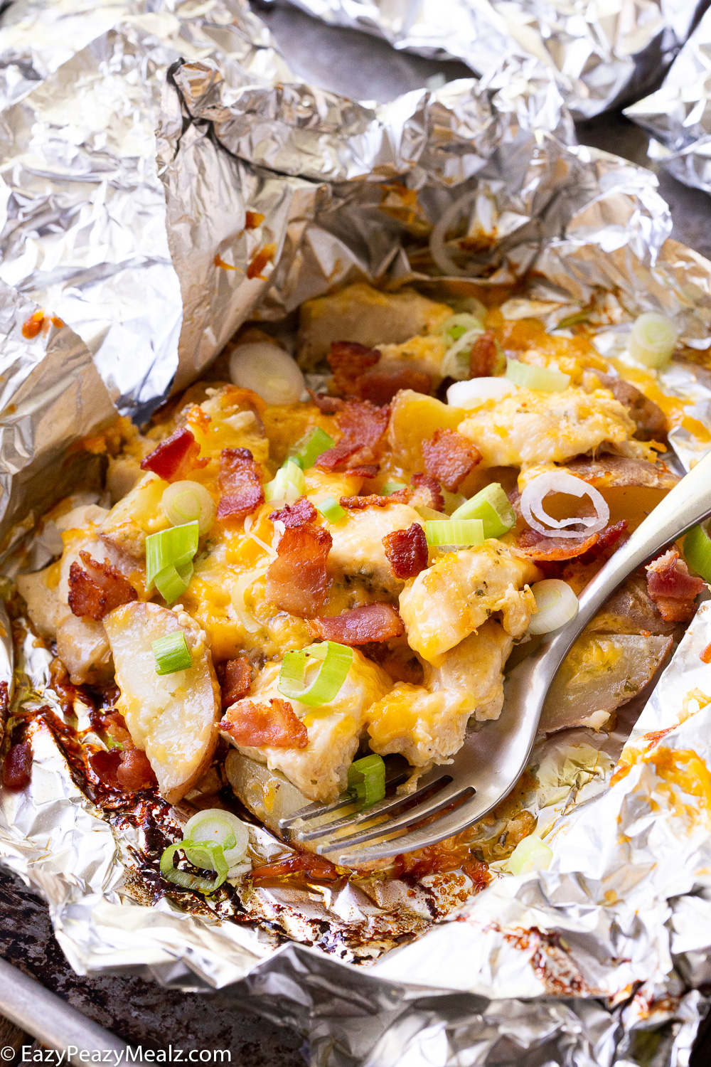 Cheesy chicken bacon ranch and potato foil pack in the foil garnished with green onion. 