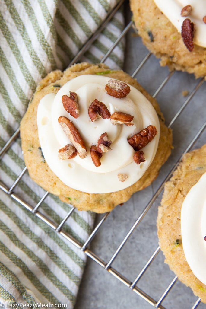 Zucchini cookies, a tender cookie studded with zucchini, and topped with cream cheese frosting and pecans.